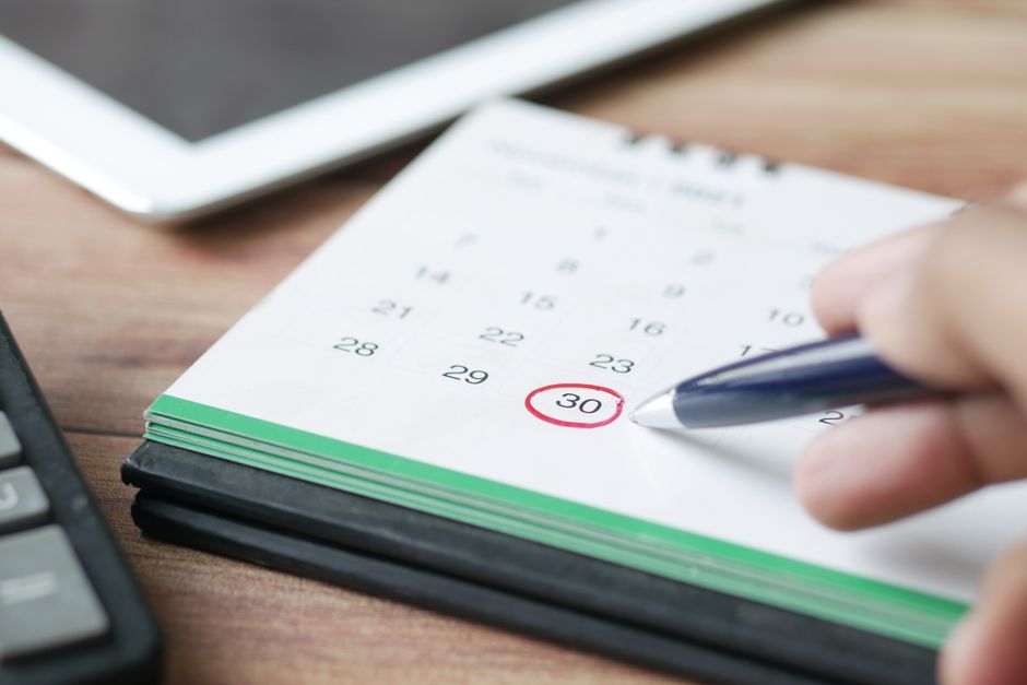 A person pointing at a calendar while planning appointment dates